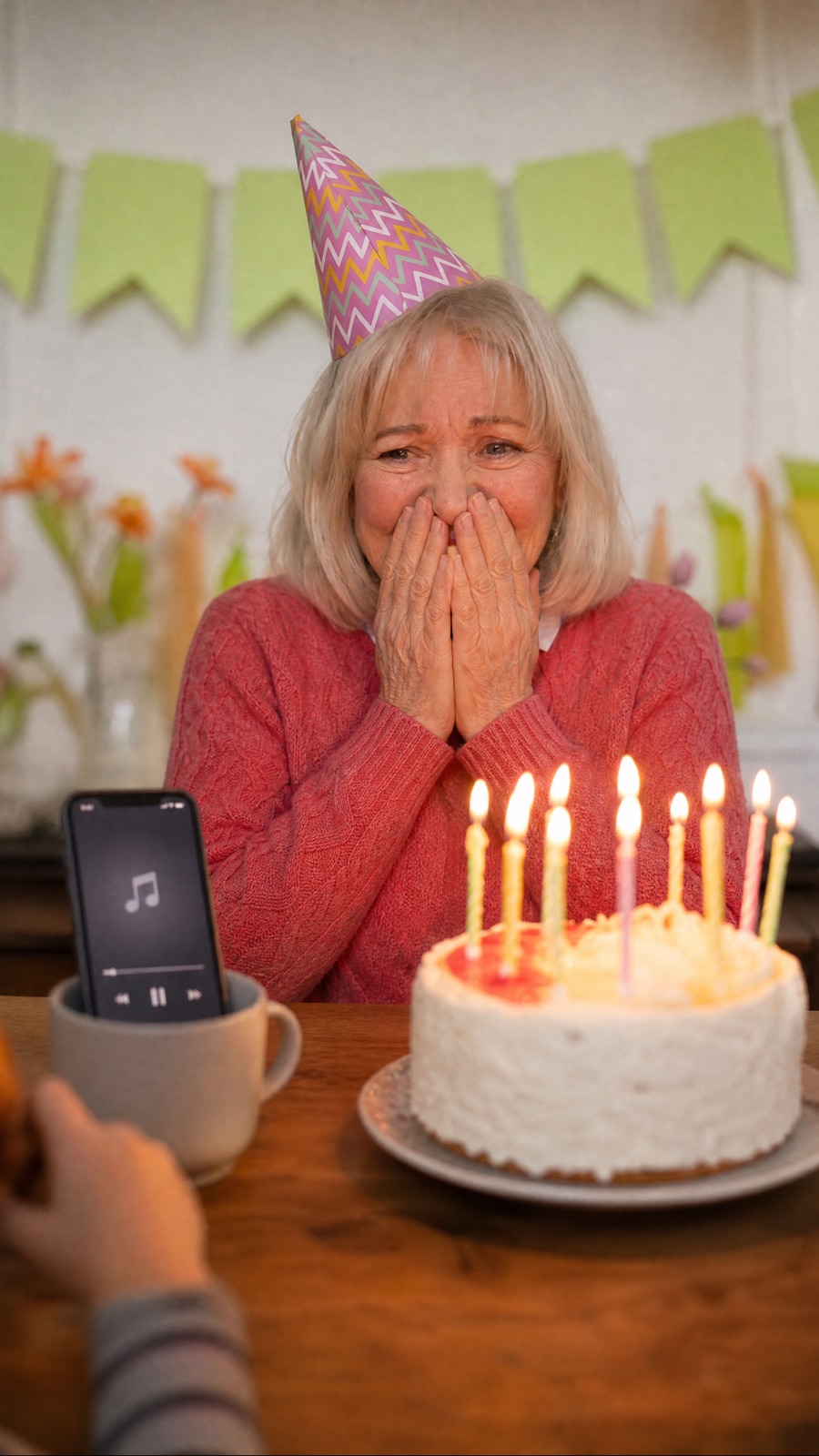 A mum at her kitchen table with a birthday cake, hands over her mouth as her kids play her song
