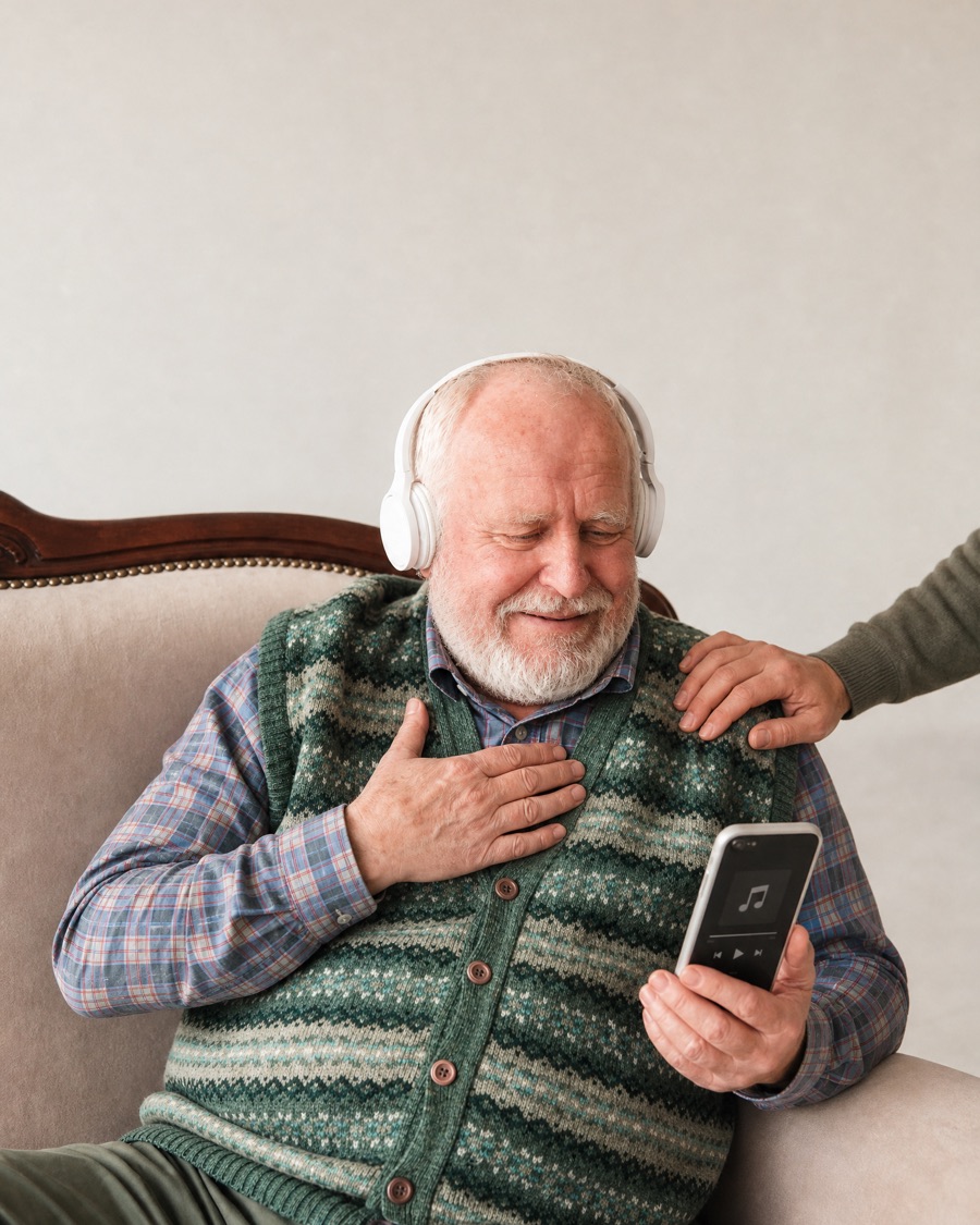 A dad on the sofa with headphones on, smiling at his song